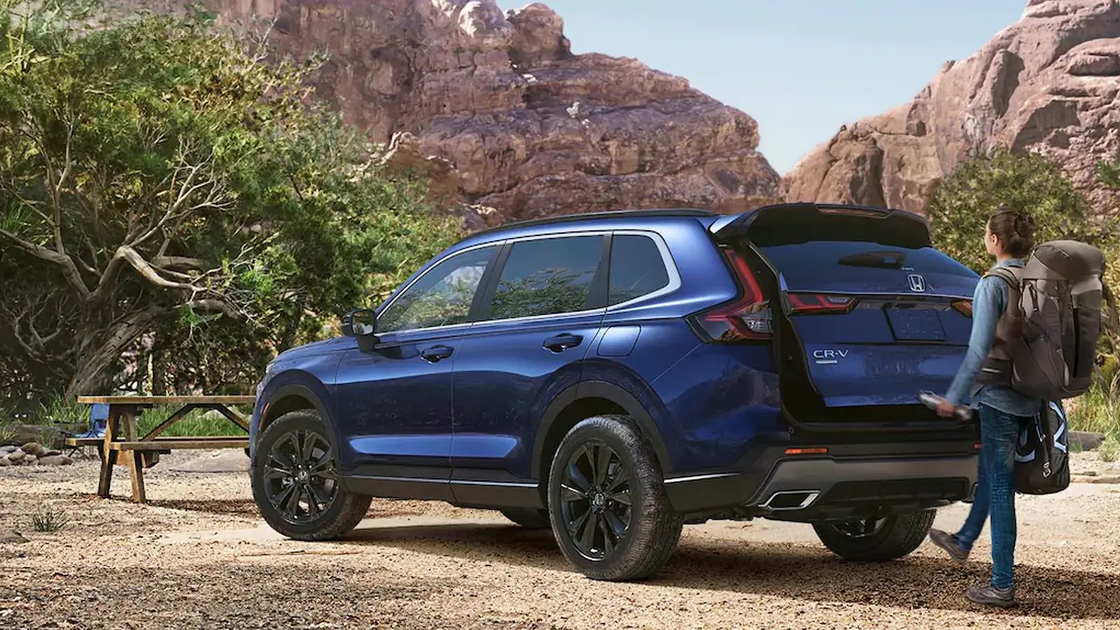 Hiker opening trunk of Honda CR-V Hybrid in a park